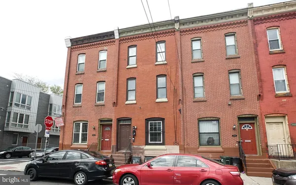 a front view of a building with cars parked