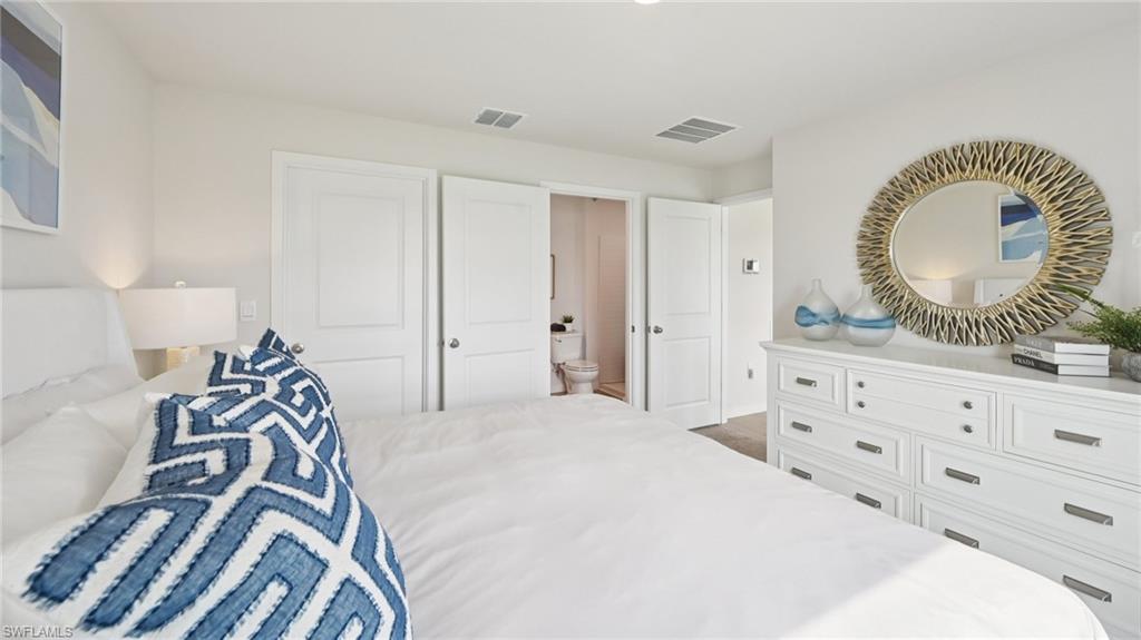 5007 3rd Street West Lehigh Acres, FL 33971 - Photo 12 of 24 Model Home. This interior space features white walls, a white dresser with drawers, and a round mirror with a decorative frame