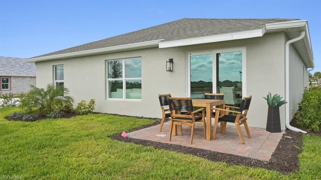 5007 3rd Street West Lehigh Acres, FL 33971 - Photo 23 of 24 Model Home. The property features a private patio with brick pavers, a well-maintained lawn, and a large sliding glass door
