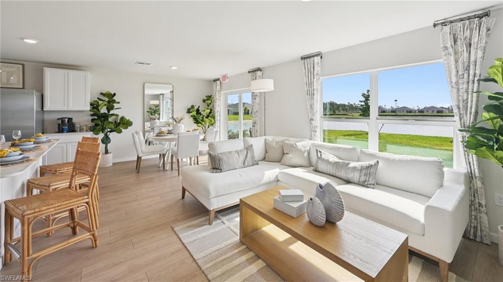 5007 3rd Street West Lehigh Acres, FL 33971 - Photo 5 of 24 Model Home. Open concept living area featuring light-toned flooring, large windows with views of a body of water, and recessed lighting