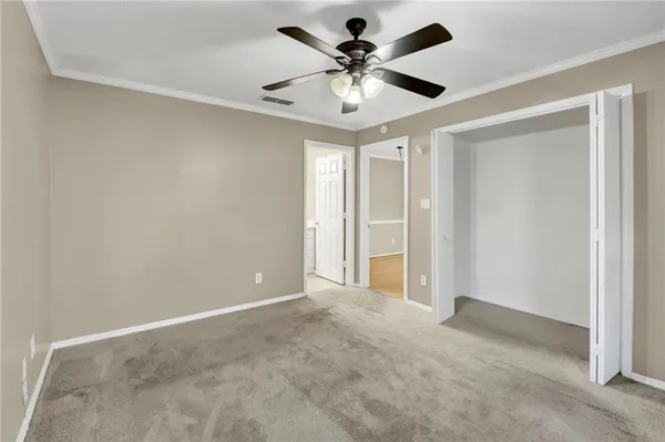 an empty room with a chandelier fan and windows