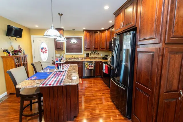 a kitchen with stainless steel appliances granite countertop a refrigerator a sink dishwasher and wooden cabinets with a large window