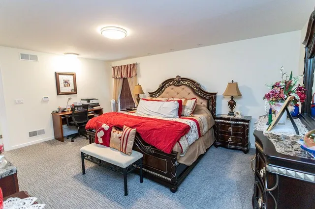 a spacious bedroom with a bed and wooden floor