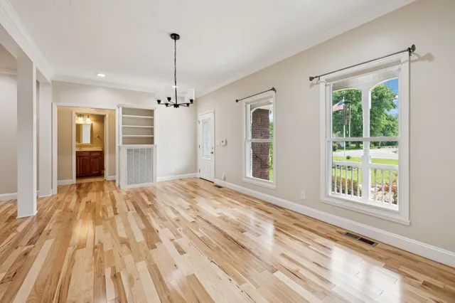 a view of a room with wooden floor chandeliers and kitchen view