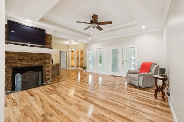 a view of a livingroom with a fireplace a ceiling fan and wooden floor