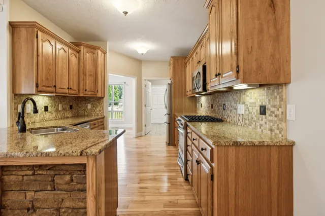 a kitchen with granite countertop a refrigerator and wooden floor