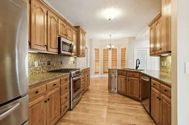 a kitchen with stainless steel appliances granite countertop a refrigerator and a stove