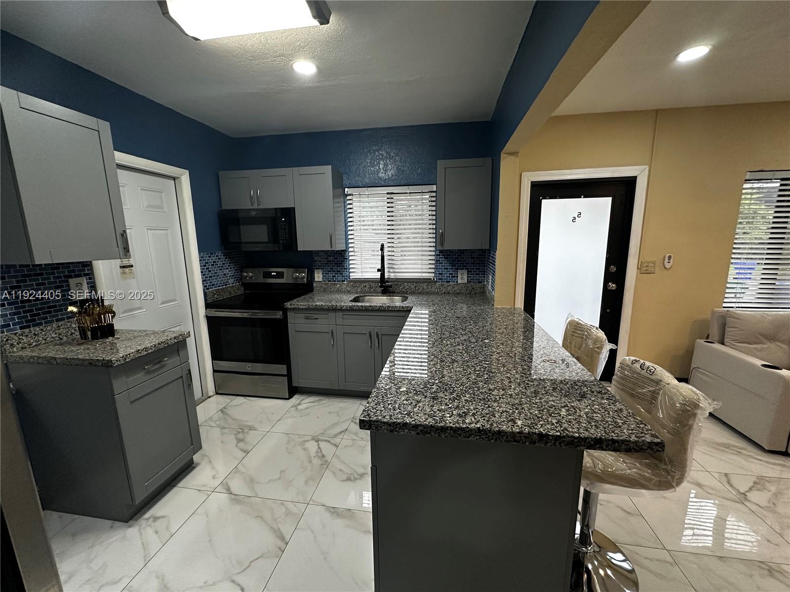 55 Northwest 44th Street Miami, FL 33127 - Photo 2 of 22 a kitchen with granite countertop stainless steel appliances a sink a counter top space cabinets and a window