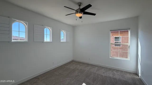 an empty room with windows and a ceiling fan