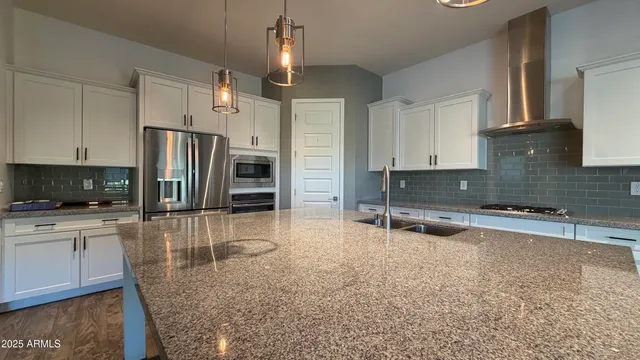 a kitchen with stainless steel appliances granite countertop a sink refrigerator and cabinets