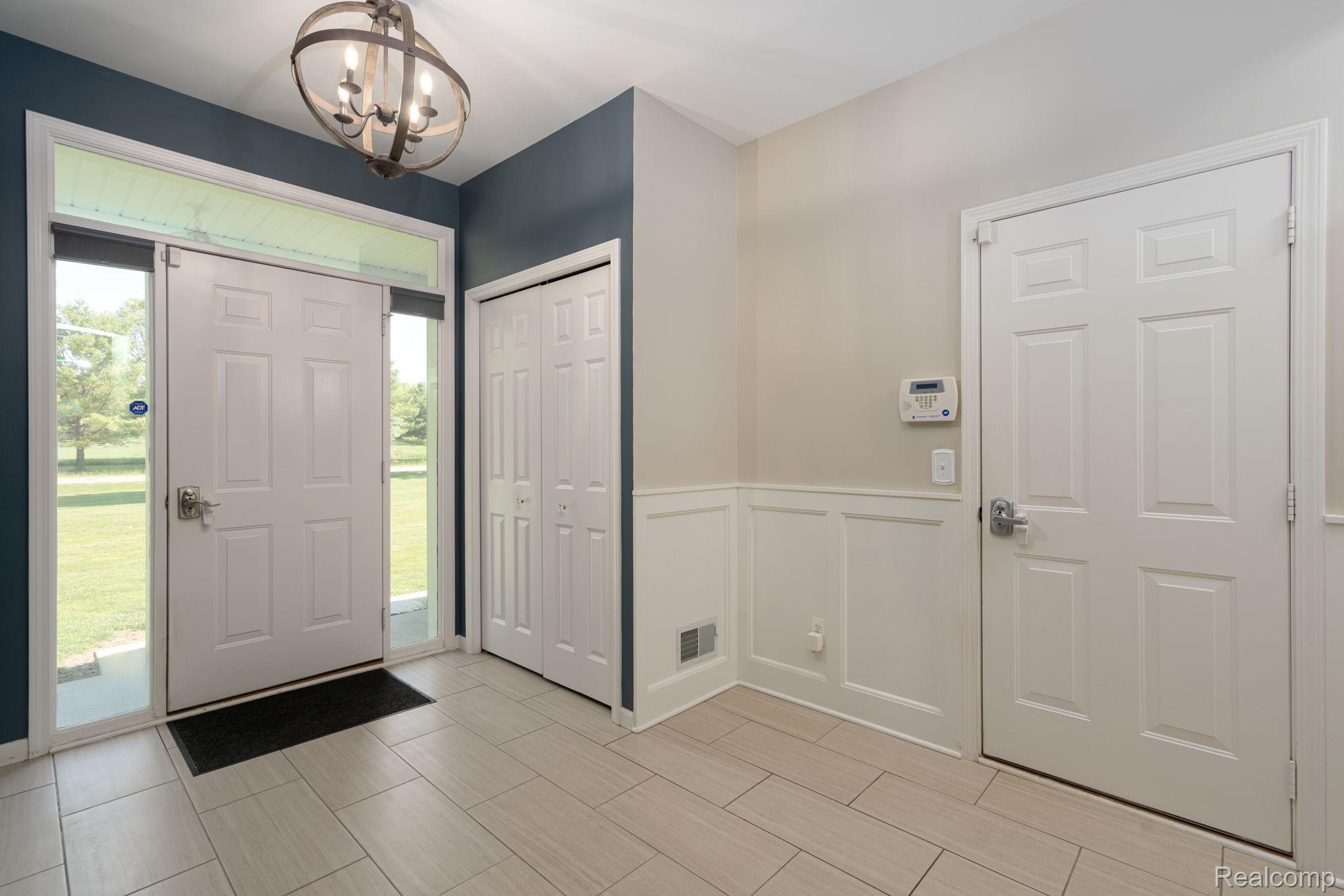 4610 East Clyde Road Howell, MI 48855 - Photo 13 of 54 Entryway featuring a panel door with sidelights, transom window, and a geometric chandelier