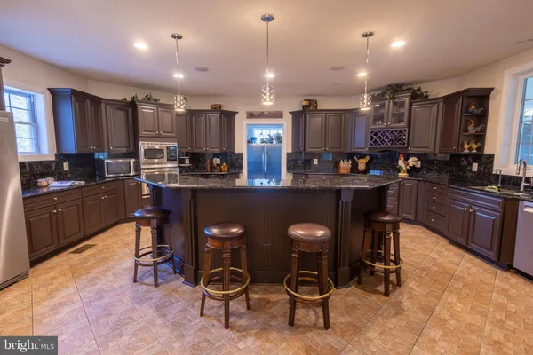 a kitchen with kitchen island granite countertop lots of counter top space and stainless steel appliances