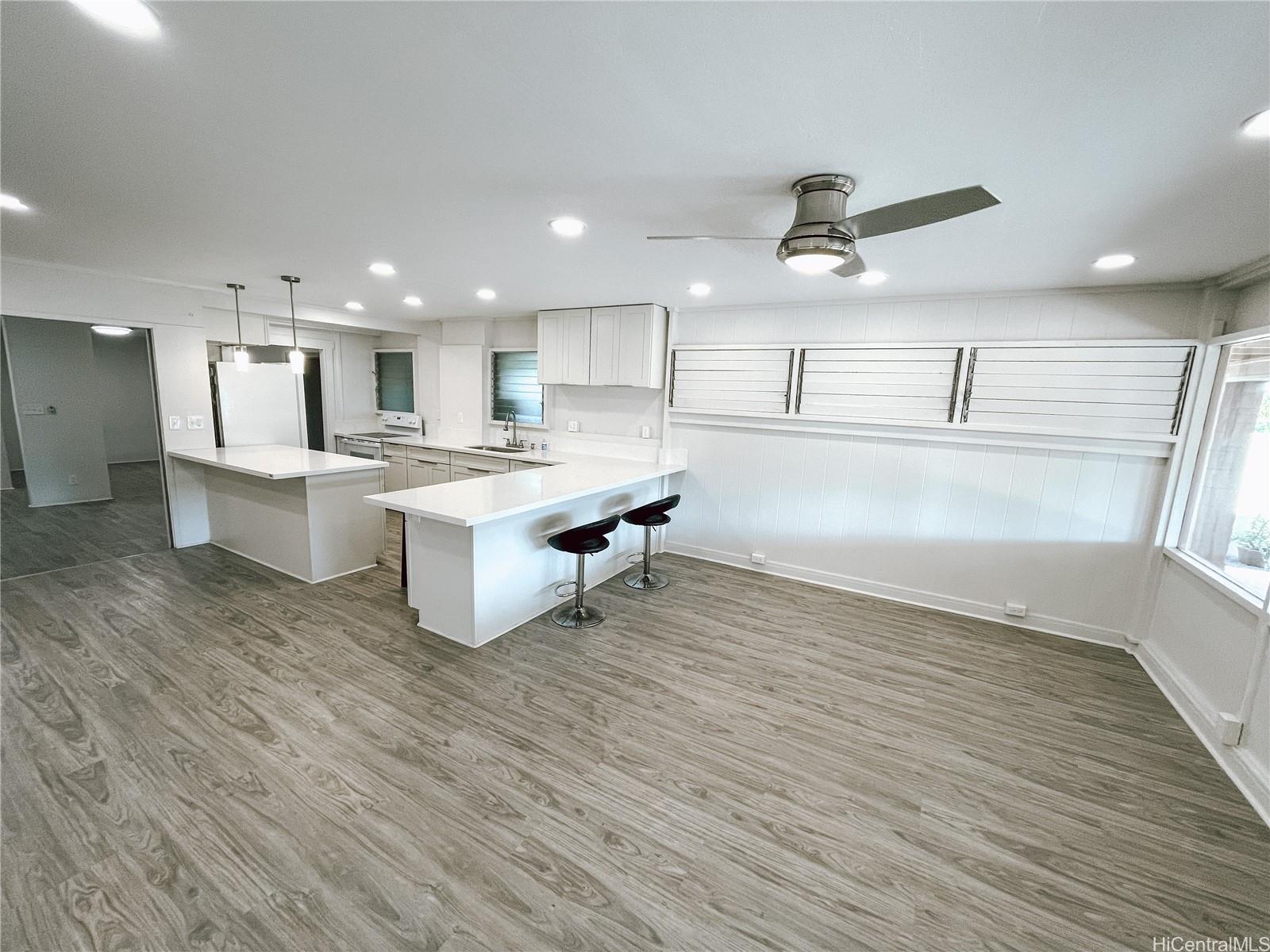 a living room with kitchen island stainless steel appliances wooden floor and a view of kitchen