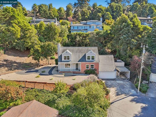 a front view of a house with a yard and large tree