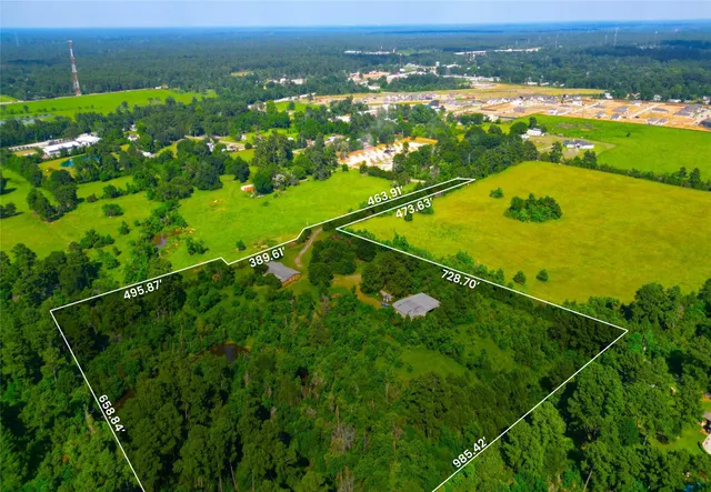 an aerial view of a residential houses with outdoor space and trees