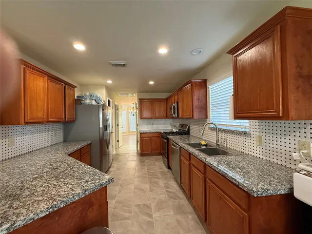 a large kitchen with stainless steel appliances granite countertop a sink stove and refrigerator