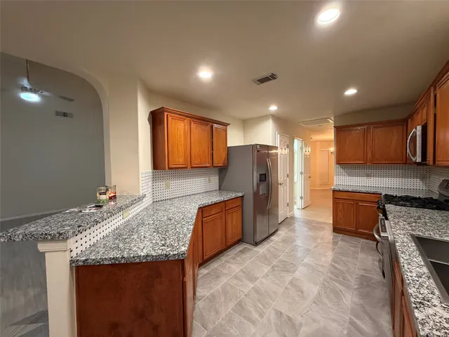 a large kitchen with stainless steel appliances granite countertop a granite counter tops and a stove