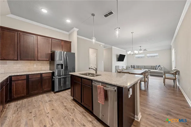 a kitchen with stainless steel appliances granite countertop a stove a refrigerator a sink dishwasher a oven with white cabinets and wooden floor