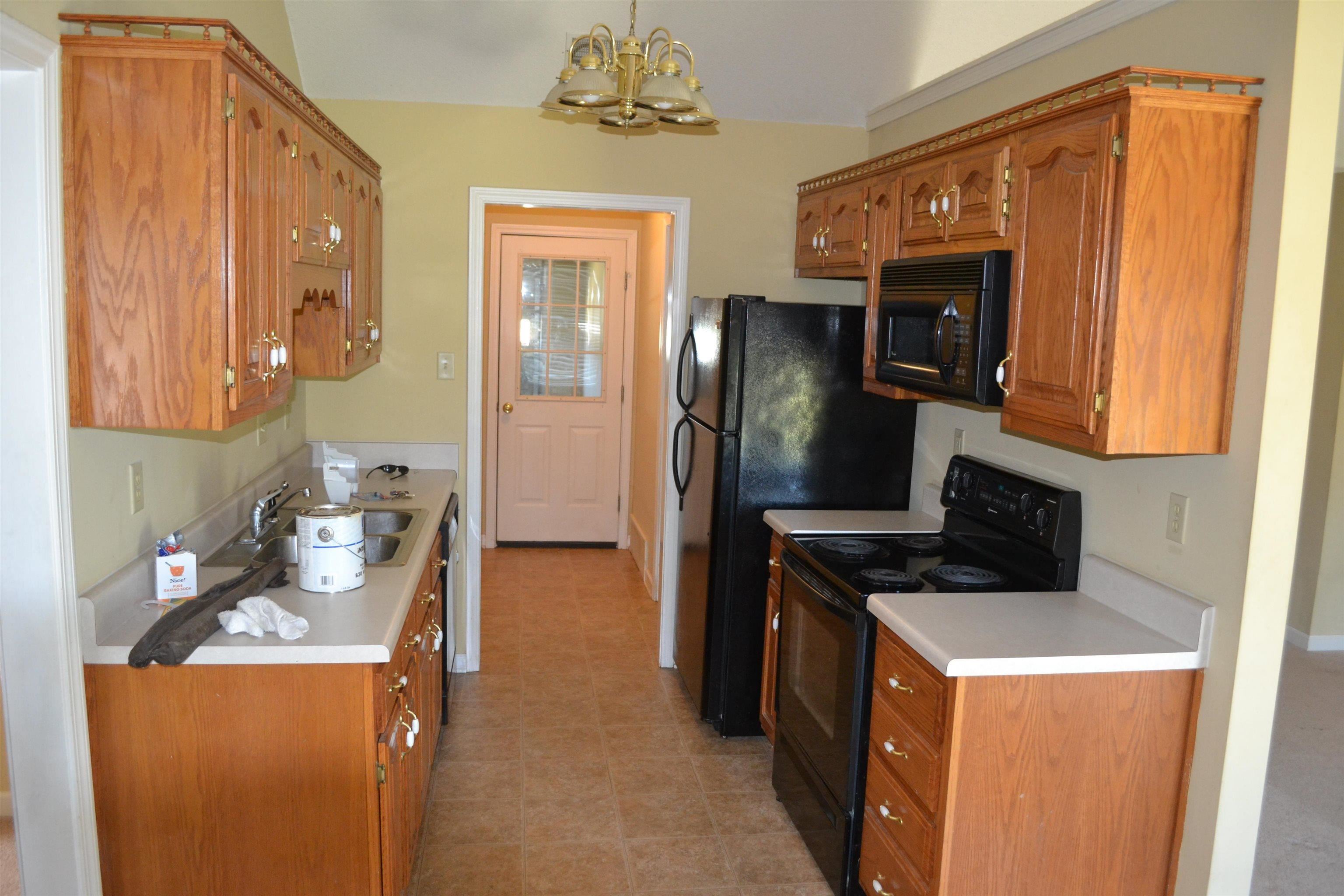 3078 Meade Lake Road Atoka, TN 38004 - Photo 4 of 8 Kitchen with black appliances, wood finish cabinetry, light countertops, and a chandelier