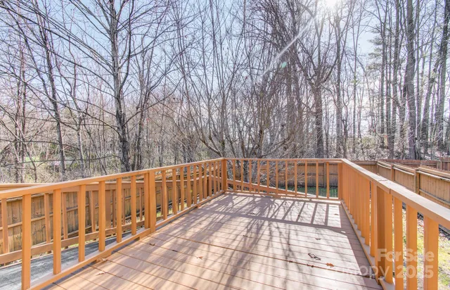 a view of a balcony with wooden fence and large trees