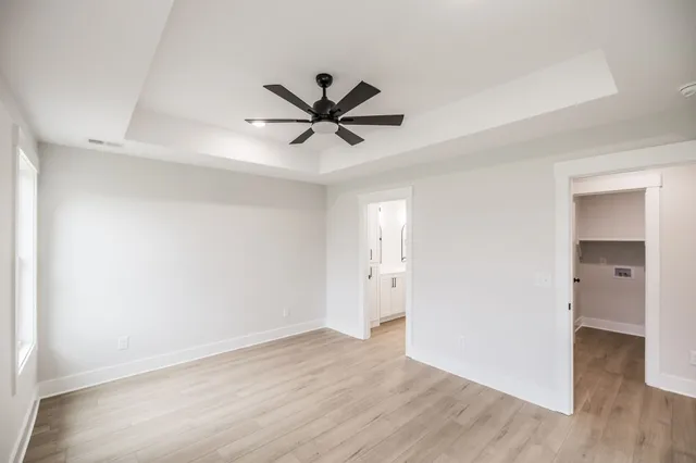 an empty room with wooden floor and a ceiling fan
