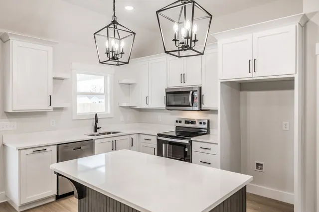 a kitchen with stainless steel appliances a table chairs cabinets and wooden floor