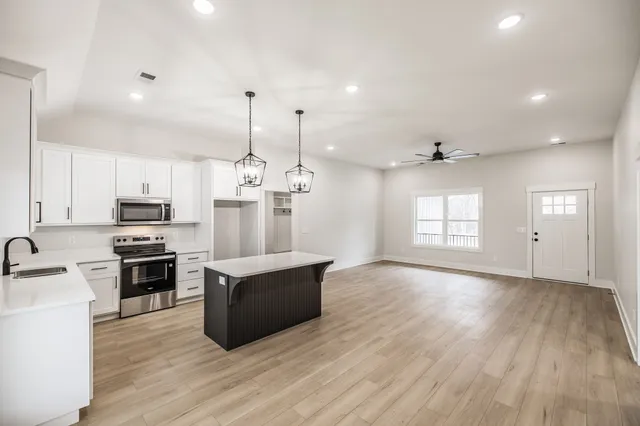 a kitchen with kitchen island white cabinets and stainless steel appliances