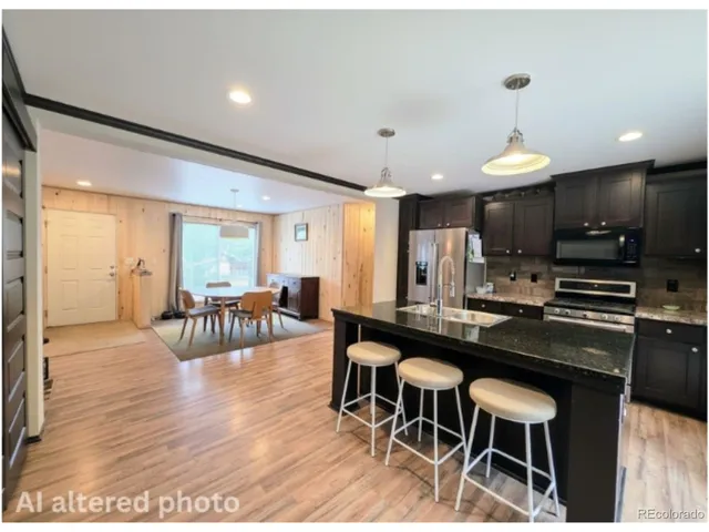 a kitchen with stainless steel appliances granite countertop a stove a refrigerator a kitchen island a dining table and chairs with wooden floor