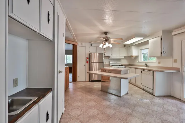 a kitchen with stainless steel appliances granite countertop a sink a stove a refrigerator and island