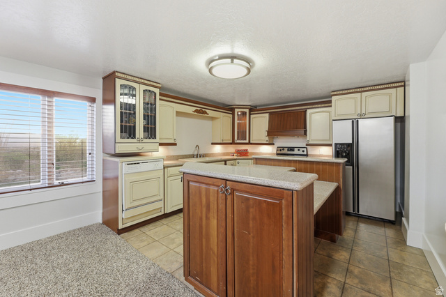 2342 Charros Road Sandy, UT 84092 - Photo 43 of 94 Kitchen featuring a central island with wood cabinetry and a light-toned countertop, tile flooring, and a stainless steel side-by-side refrigerator