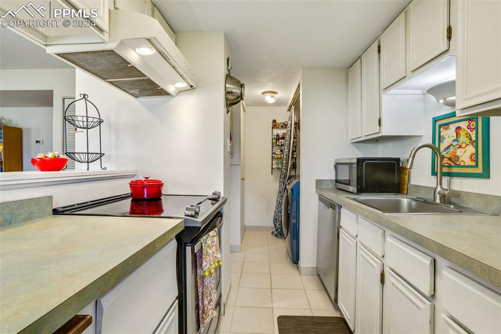 1098 Fontmore Road, Unit B Colorado Springs, CO 80904 - Photo 9 of 27 Kitchen with light tile patterned floors, sink, extractor fan, white cabinetry, and appliances with stainless steel finishes