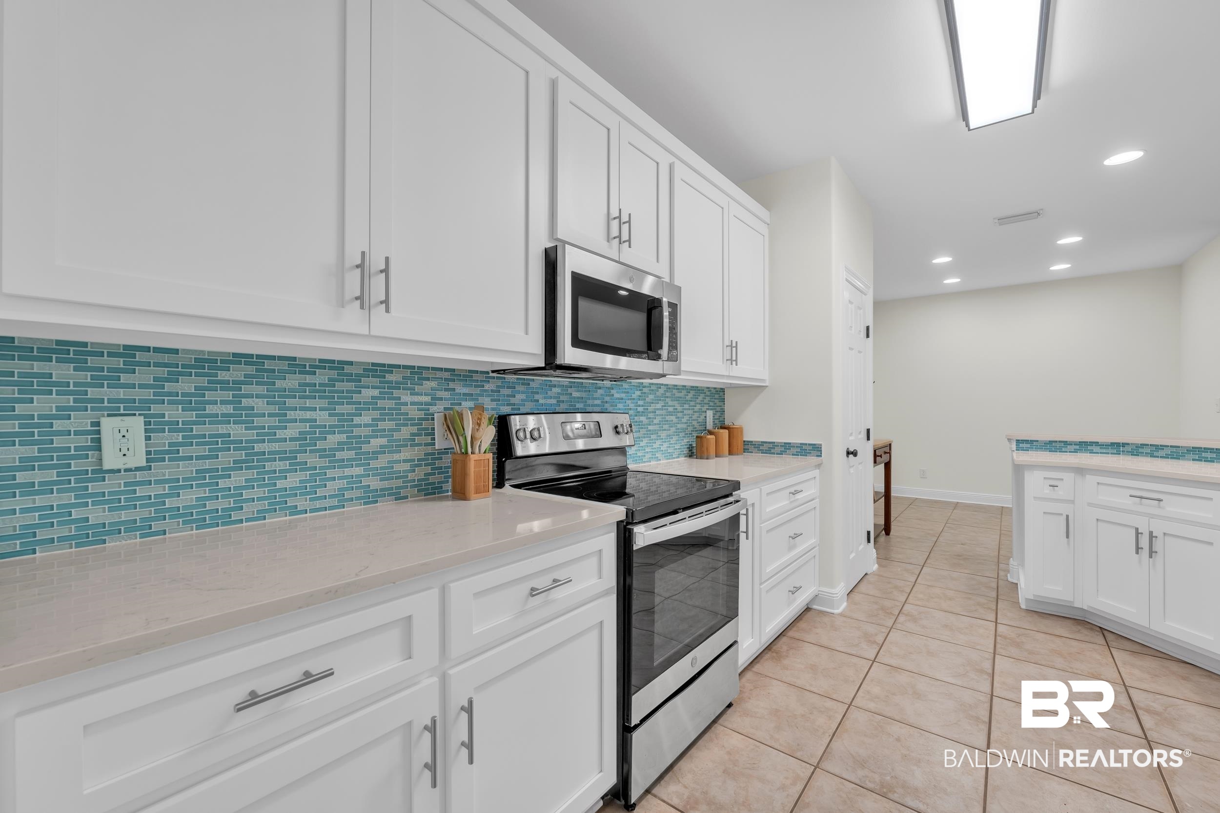4606 Osprey Drive Orange Beach, AL 36561 - Photo 21 of 44 Kitchen with appliances with stainless steel finishes, tasteful backsplash, white cabinets, light tile patterned floors, and recessed lighting