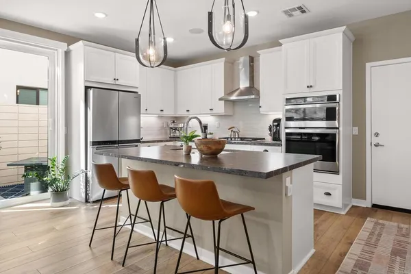 a kitchen with stainless steel appliances granite countertop a sink a stove a refrigerator cabinets and chairs