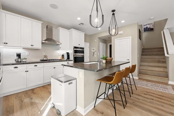 a kitchen with stainless steel appliances granite countertop a sink a stove a dining table and chairs with wooden floor