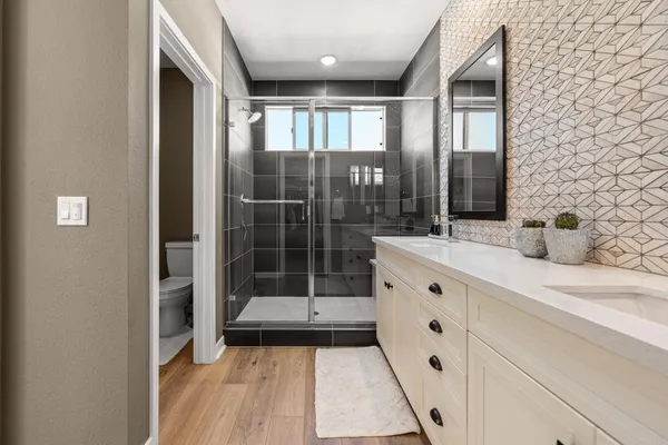 a bathroom with a double vanity sink a toilet and shower