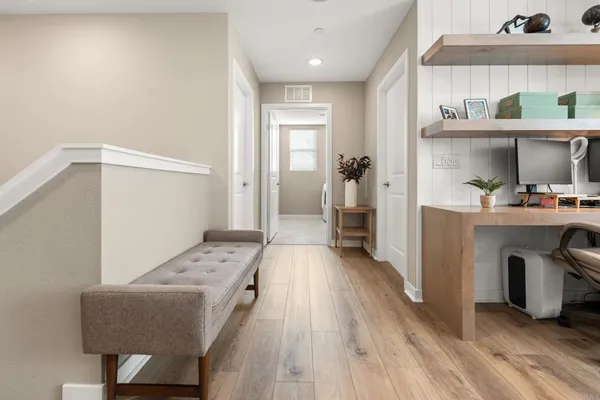 a walk in closet with wooden floor and cabinets
