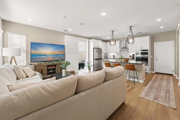 a living room with stainless steel appliances furniture and a flat screen tv