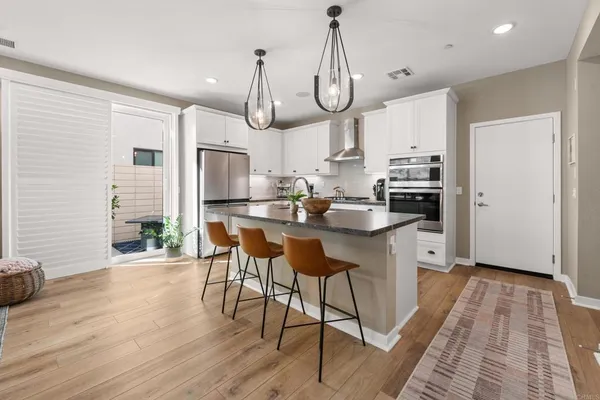 a kitchen with stainless steel appliances a kitchen island hardwood floor sink stove and white cabinets