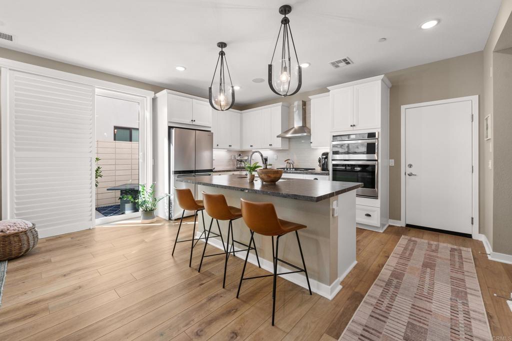 13085 Olympus Circle, Unit 1 Poway, CA 92064 - Photo 8 of 44 a kitchen with stainless steel appliances a kitchen island hardwood floor sink stove and white cabinets