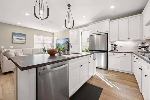 a kitchen with stainless steel appliances a sink a stove a refrigerator cabinets and chairs