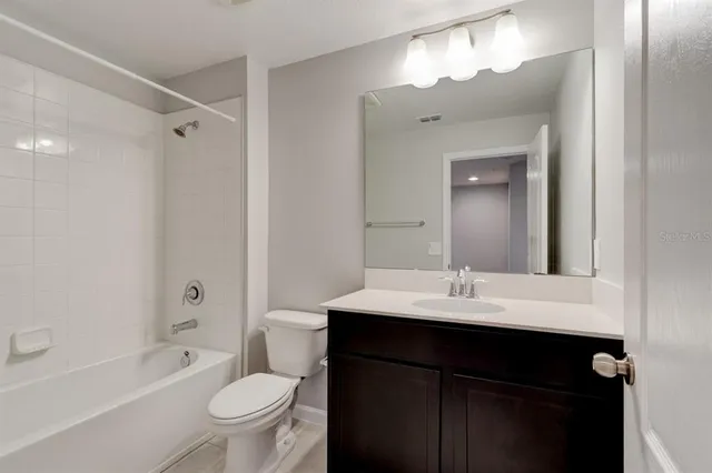 a bathroom with a sink a toilet a mirror a vanity and shower