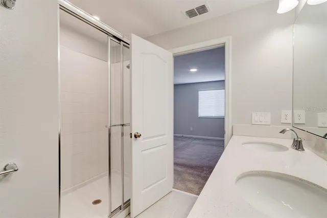 a bathroom with a granite countertop sink a mirror and shower