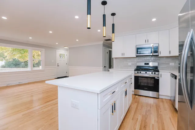 a kitchen with stainless steel appliances a refrigerator a sink a stove a microwave and wooden floor