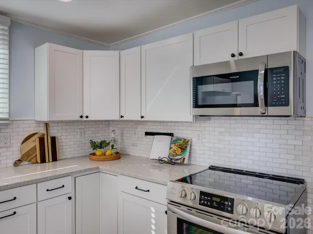 a kitchen with stainless steel appliances granite countertop white cabinets a stove a sink and dishwasher