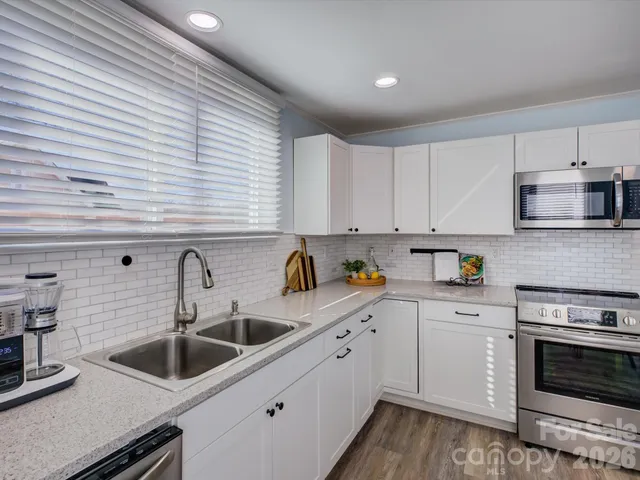 a kitchen with white cabinets a sink and appliances
