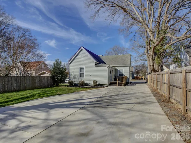 a view of a house with a yard and large trees