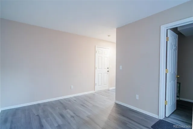 a view of an empty room with wooden floor and closet