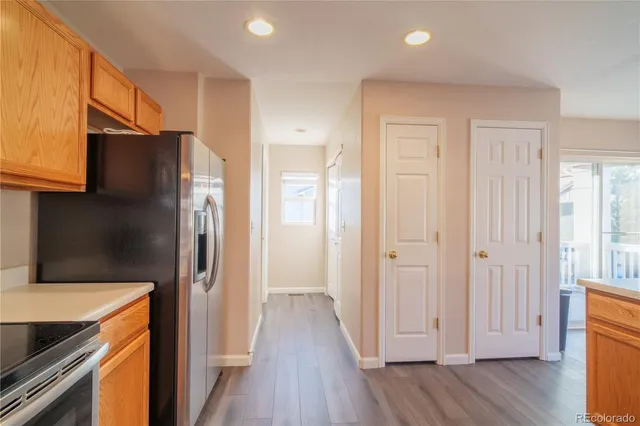 a kitchen with a refrigerator an oven and wooden floor