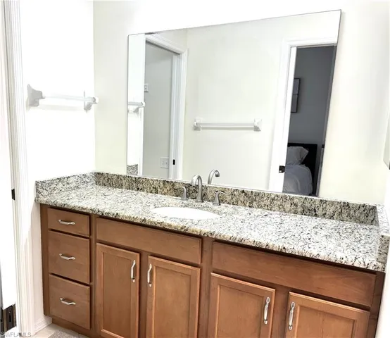 a bathroom with a granite countertop sink and a mirror