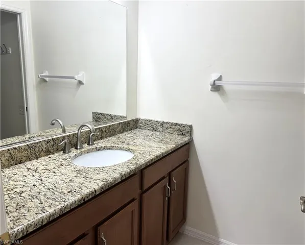 a bathroom with a granite countertop sink and a mirror